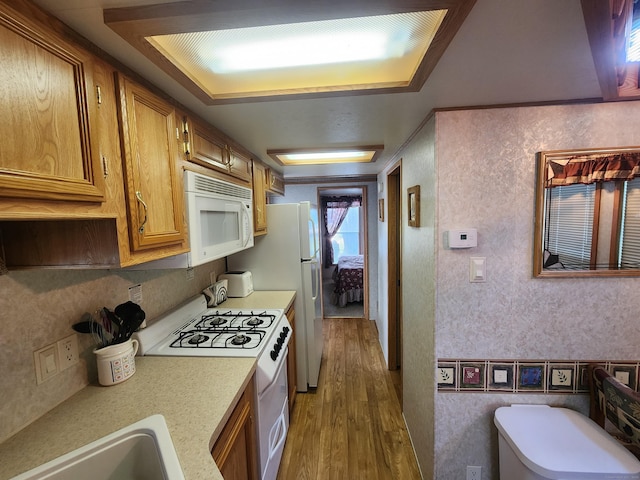 kitchen with wood-type flooring, white appliances, and sink