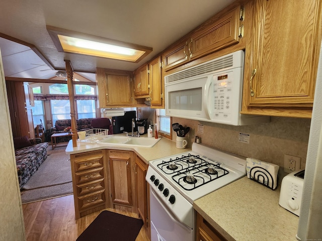 kitchen with white appliances, sink, light hardwood / wood-style flooring, ceiling fan, and kitchen peninsula