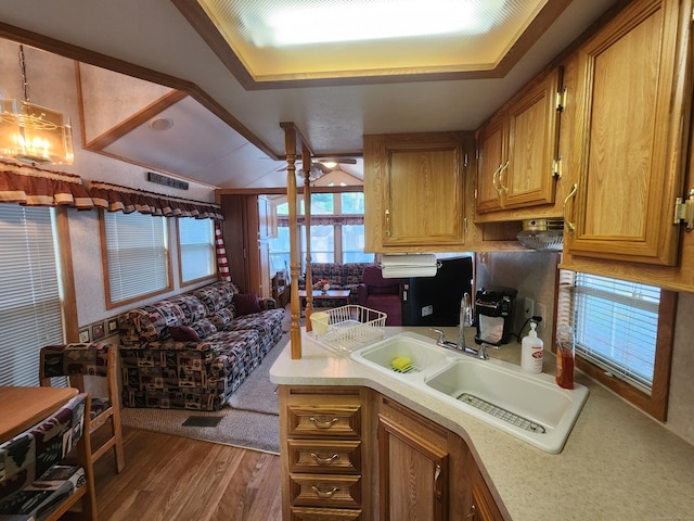 kitchen featuring sink, dark hardwood / wood-style floors, a notable chandelier, kitchen peninsula, and a tray ceiling