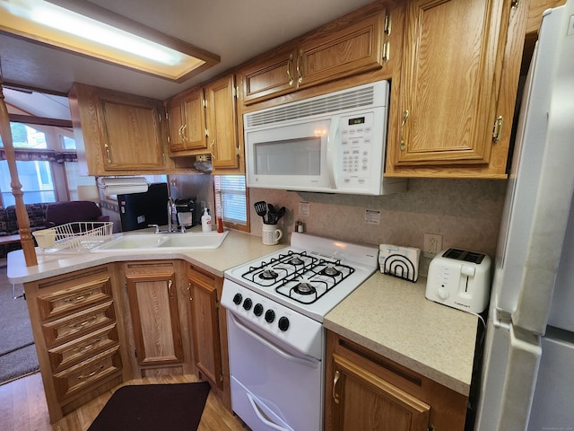 kitchen featuring kitchen peninsula, sink, light hardwood / wood-style floors, and white appliances