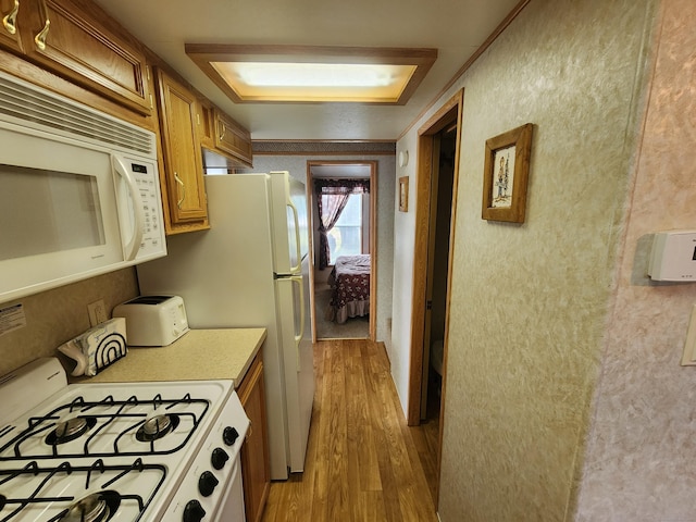 kitchen featuring white appliances, light hardwood / wood-style flooring, and ornamental molding