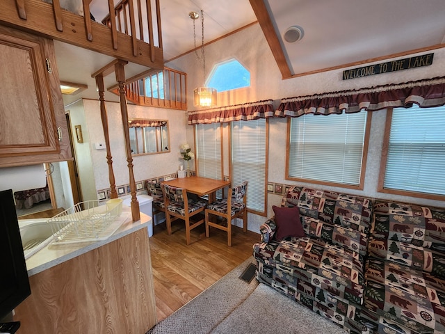 dining room with light hardwood / wood-style floors, ornamental molding, and high vaulted ceiling