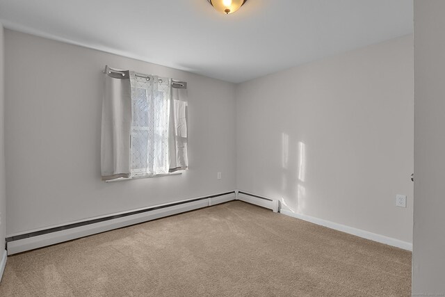 unfurnished room featuring baseboard heating and carpet