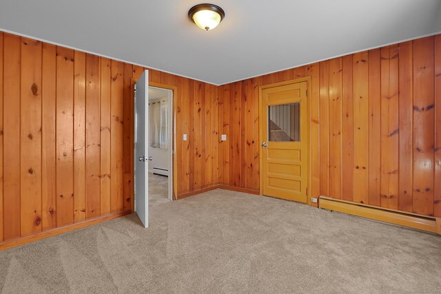 carpeted spare room with baseboard heating and wooden walls