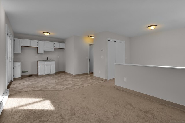 unfurnished living room featuring light carpet and sink