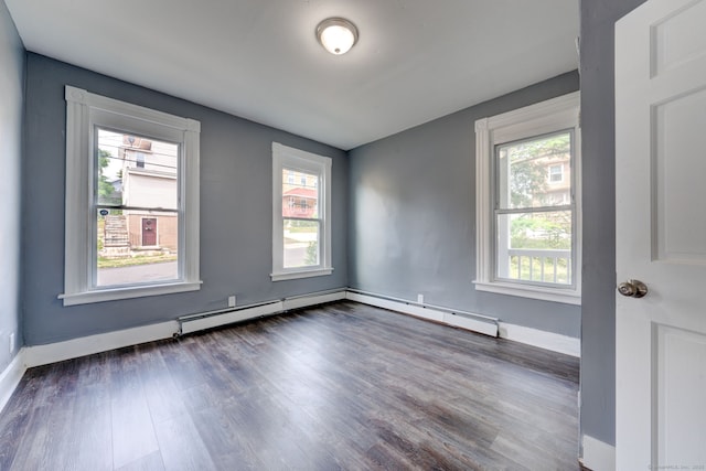 spare room featuring a baseboard heating unit, plenty of natural light, and dark wood-type flooring