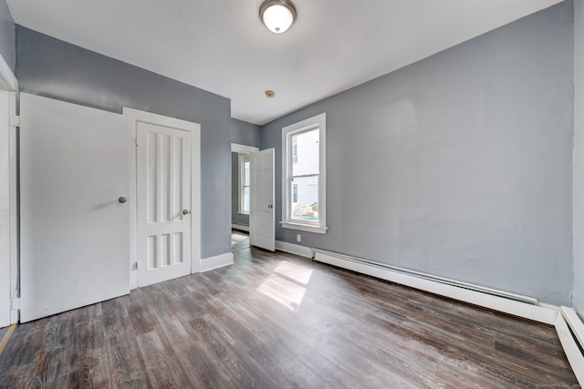 empty room featuring wood-type flooring and a baseboard radiator