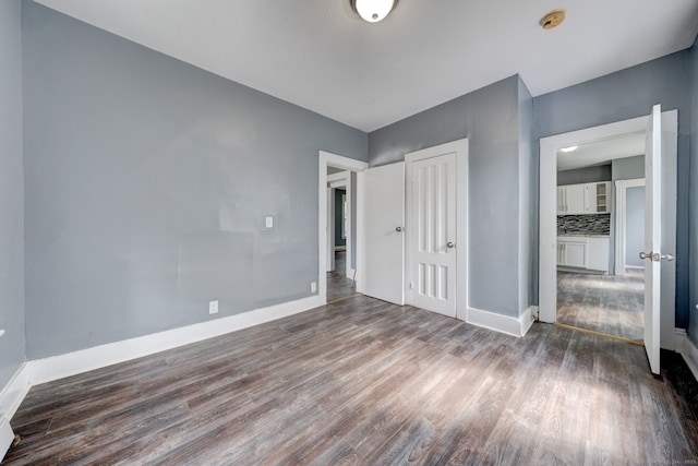 unfurnished bedroom featuring a closet and dark wood-type flooring