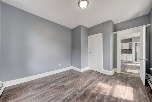 unfurnished bedroom featuring a baseboard radiator and hardwood / wood-style flooring