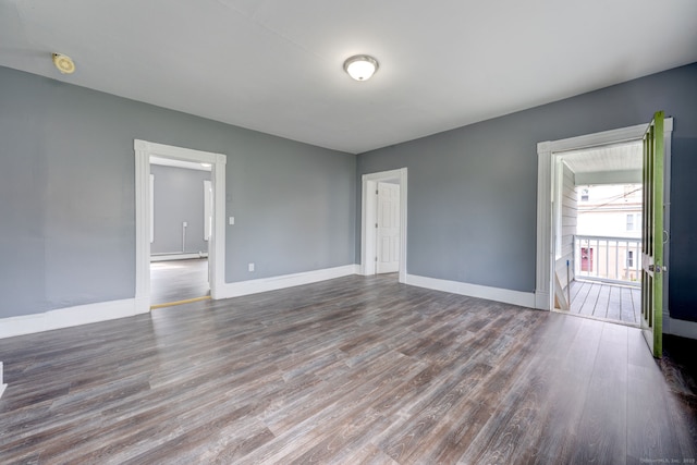 empty room featuring dark hardwood / wood-style floors and a baseboard heating unit