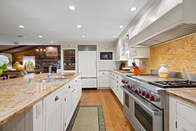 kitchen featuring white cabinets, sink, built in appliances, light hardwood / wood-style floors, and custom range hood