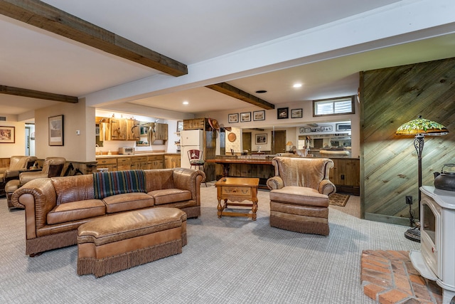 living room with beam ceiling, wooden walls, and light colored carpet