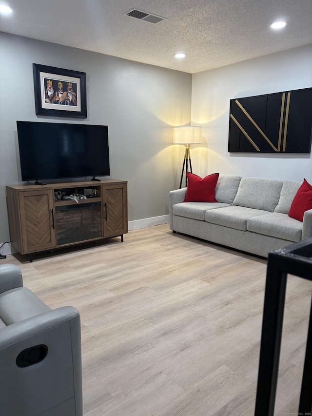 living room featuring light hardwood / wood-style flooring and a textured ceiling