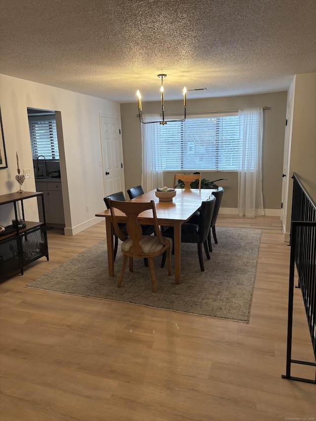 dining room with sink, plenty of natural light, an inviting chandelier, and light wood-type flooring