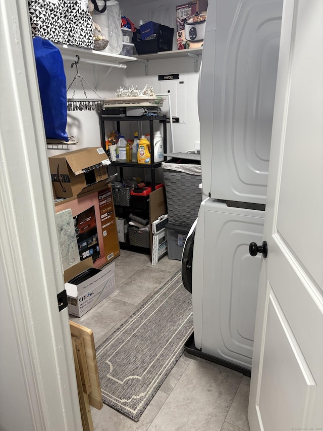 laundry area featuring stacked washer and dryer and light tile patterned flooring