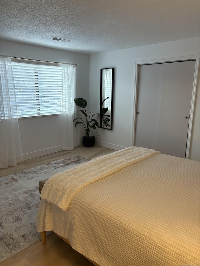 bedroom featuring wood-type flooring, a textured ceiling, and a closet