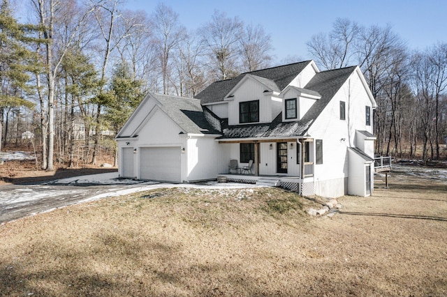 view of front of property with a front yard, a garage, and a porch