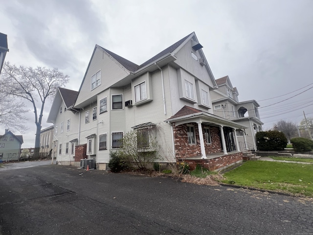 view of side of home with a lawn, cooling unit, and covered porch