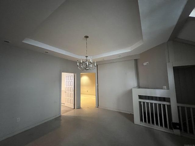 unfurnished room with a chandelier and a tray ceiling