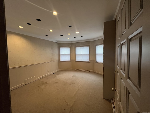 carpeted empty room with a baseboard heating unit