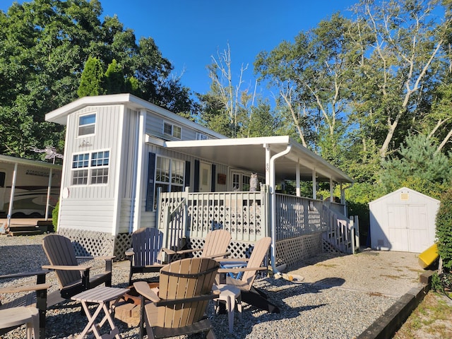 rear view of property featuring a porch and a storage shed