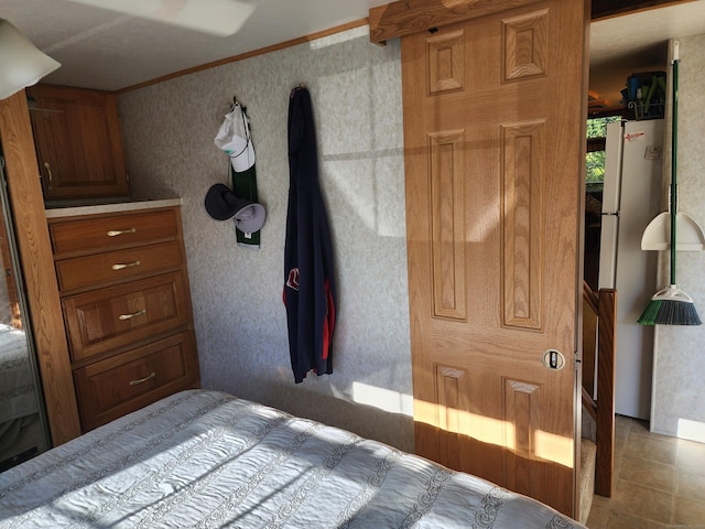 bedroom featuring stainless steel refrigerator and crown molding