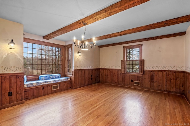 empty room with light hardwood / wood-style floors and a chandelier