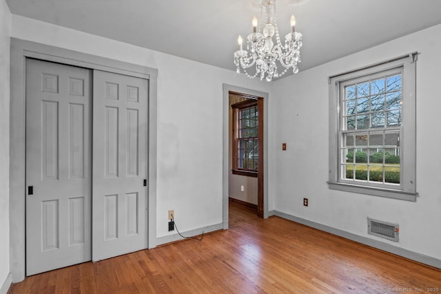 unfurnished bedroom with a closet, light hardwood / wood-style floors, and a chandelier