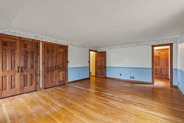 unfurnished bedroom with light wood-type flooring and multiple closets