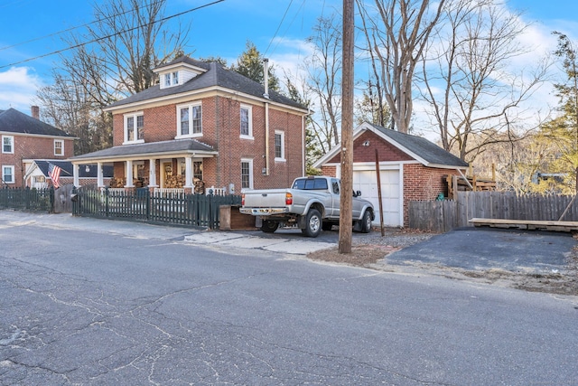 view of property featuring covered porch, a garage, and an outdoor structure