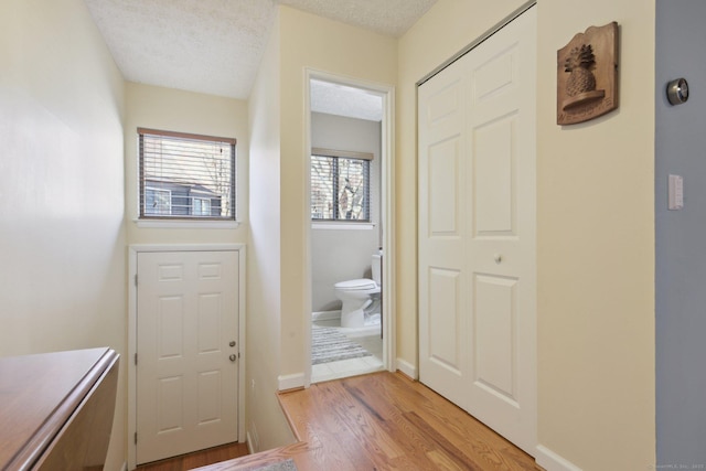 doorway to outside with light hardwood / wood-style floors and a textured ceiling