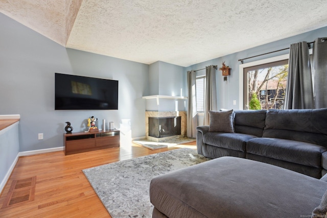 living room featuring hardwood / wood-style floors, a premium fireplace, and a textured ceiling