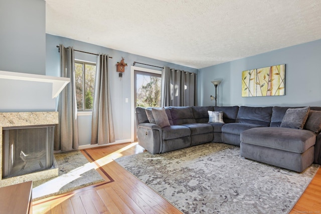 living room with a premium fireplace, wood-type flooring, and a textured ceiling