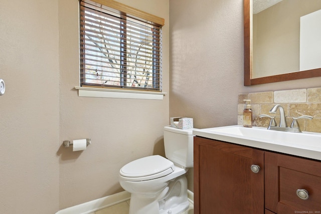 bathroom featuring vanity, toilet, and decorative backsplash