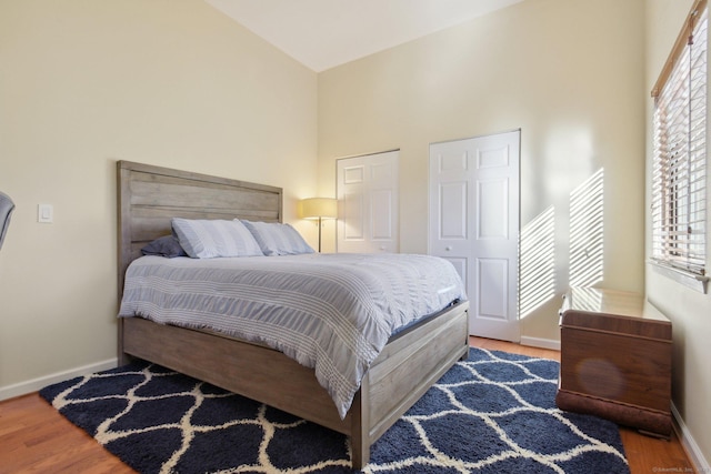 bedroom with hardwood / wood-style flooring, high vaulted ceiling, and multiple windows