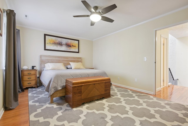 bedroom with ceiling fan, crown molding, and light hardwood / wood-style flooring