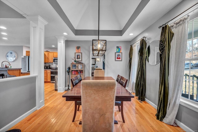 dining area with a raised ceiling, light wood-type flooring, a wealth of natural light, and vaulted ceiling