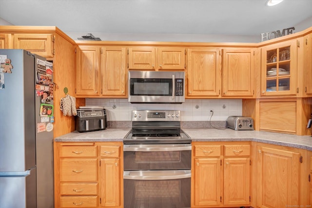 kitchen featuring decorative backsplash, light brown cabinets, and stainless steel appliances