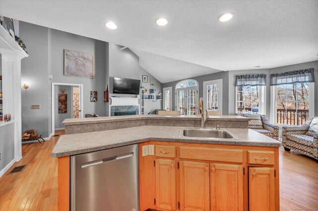 kitchen featuring light wood-type flooring, sink, a center island with sink, dishwasher, and lofted ceiling