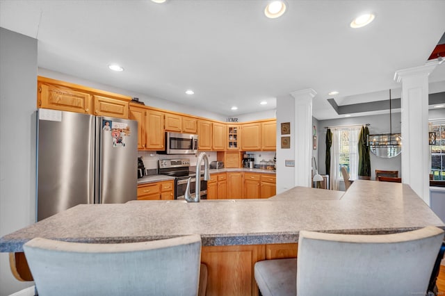 kitchen with a kitchen breakfast bar, sink, ornate columns, light brown cabinetry, and stainless steel appliances