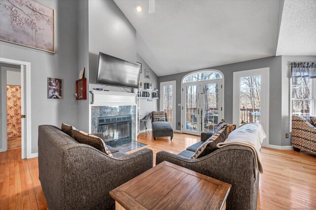 living room featuring a high end fireplace, light hardwood / wood-style floors, and high vaulted ceiling