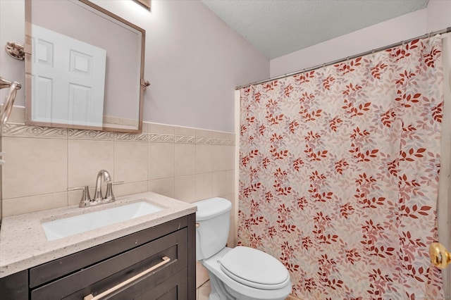 bathroom with vanity, toilet, a textured ceiling, tile walls, and walk in shower