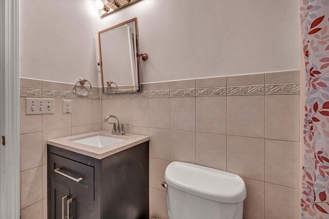 bathroom featuring a shower with shower curtain, vanity, toilet, and tile walls