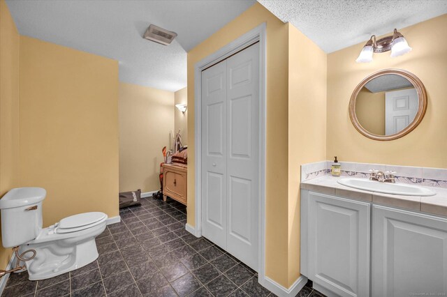 bathroom with vanity, toilet, and a textured ceiling