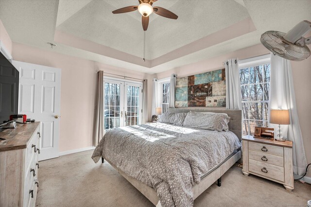 bedroom with french doors, a textured ceiling, light colored carpet, a raised ceiling, and ceiling fan