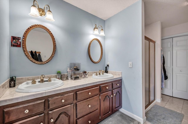 bathroom featuring tile patterned flooring, vanity, a textured ceiling, and a shower with shower door