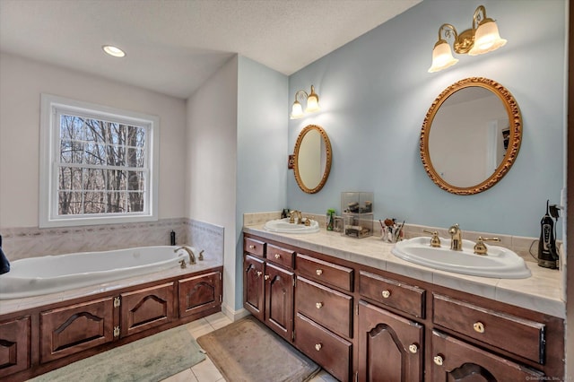 bathroom featuring a washtub, vanity, a textured ceiling, and tile patterned floors