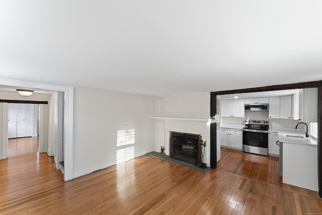 unfurnished living room featuring light hardwood / wood-style flooring and sink