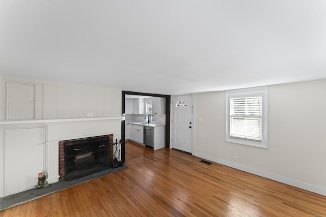 unfurnished living room featuring a brick fireplace and hardwood / wood-style flooring