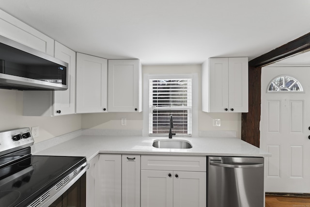 kitchen featuring appliances with stainless steel finishes, white cabinetry, and sink